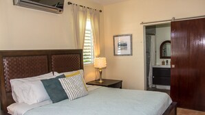 A bedroom with a bed, a nightstand, a lamp, a framed picture, and a wooden door. - Family time, 5 minute walk from main walkway to restaurants and beach! (Vieques)