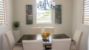 A dining area with a rectangular table, six upholstered chairs, a chandelier, and two wall-mounted paintings. - Family time, 5 minute walk from main walkway to restaurants and beach! (Vieques)