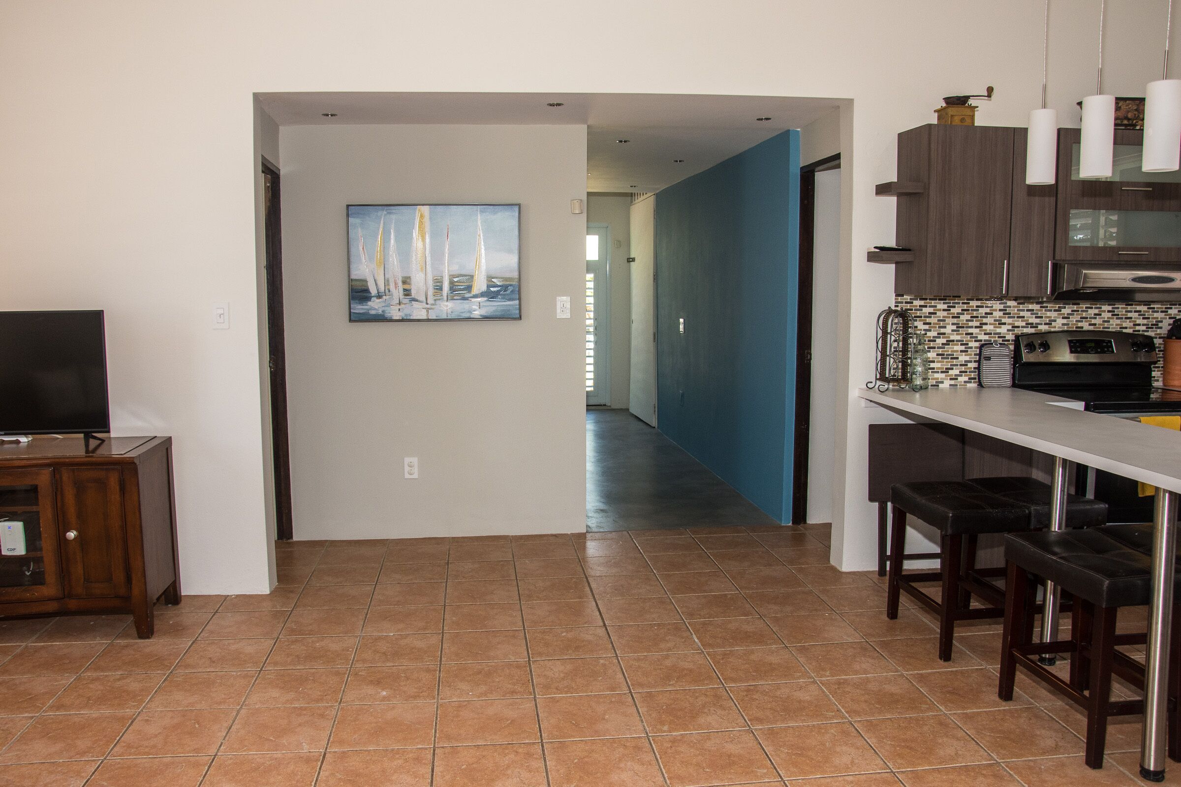 A modern kitchen with a tiled backsplash, stainless steel appliances, and bar stools.