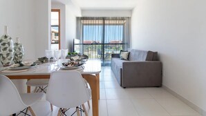Una sala moderna con comedor, un sofá gris y un ventanal con cortinas.