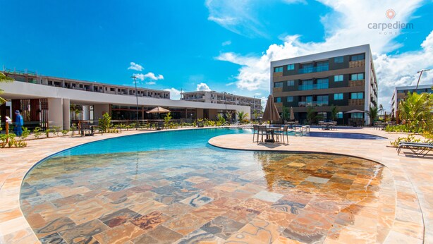 Una piscina con un diseño de azulejos único, rodeada por un edificio moderno de varios pisos y balcones.