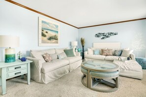 Ein Wohnzimmer mit zwei beigen Sofas, einem Glastisch und einem kleinen Beistelltisch mit einer Lampe.