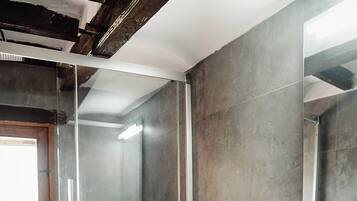 Un baño moderno con cabina de ducha de vidrio, inodoro blanco y tocador de madera con espejo.