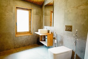 A bathroom with a wooden vanity, a sink, a toilet, and a shower. - Cases Altes de Posada (Navès)