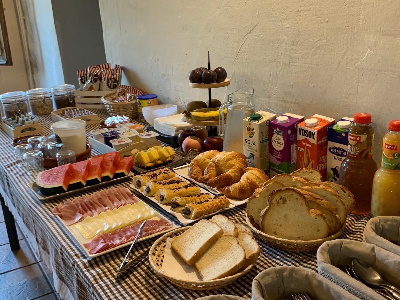 Una mesa de bufé con diversos alimentos, como carnes, quesos, pasteles y pan.