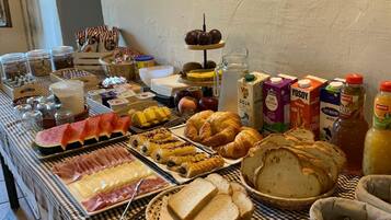 Una mesa de bufé con diversos alimentos, como carnes, quesos, pasteles y pan.