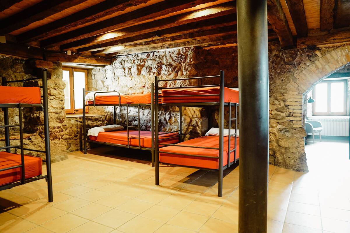 A rustic room with bunk beds, stone walls, and a wooden ceiling.