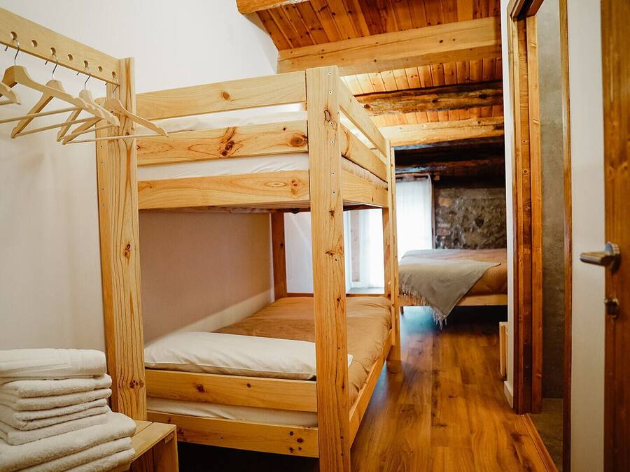 A wooden bunk bed room with a wooden wardrobe and a stack of towels.