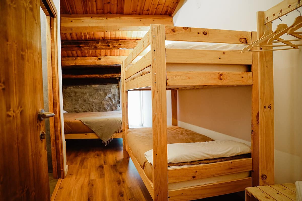 A wooden bunk bed room with a stone wall and a wooden door.