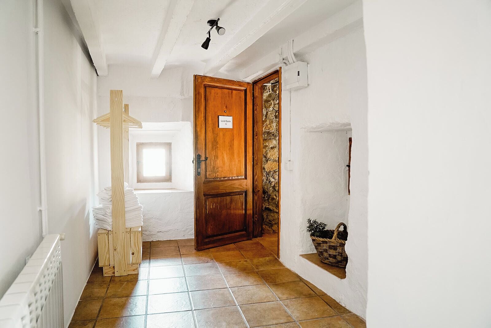 Un couloir avec une porte en bois portant l’inscription « Suite de Lord », un radiateur, une fenêtre et un sol carrelé.