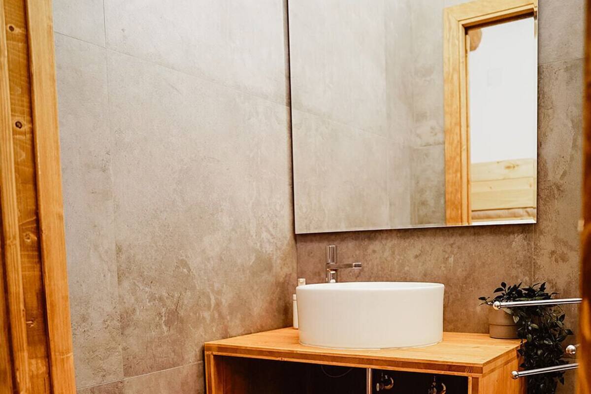 A bathroom with a wooden vanity, a white sink, and a mirror.