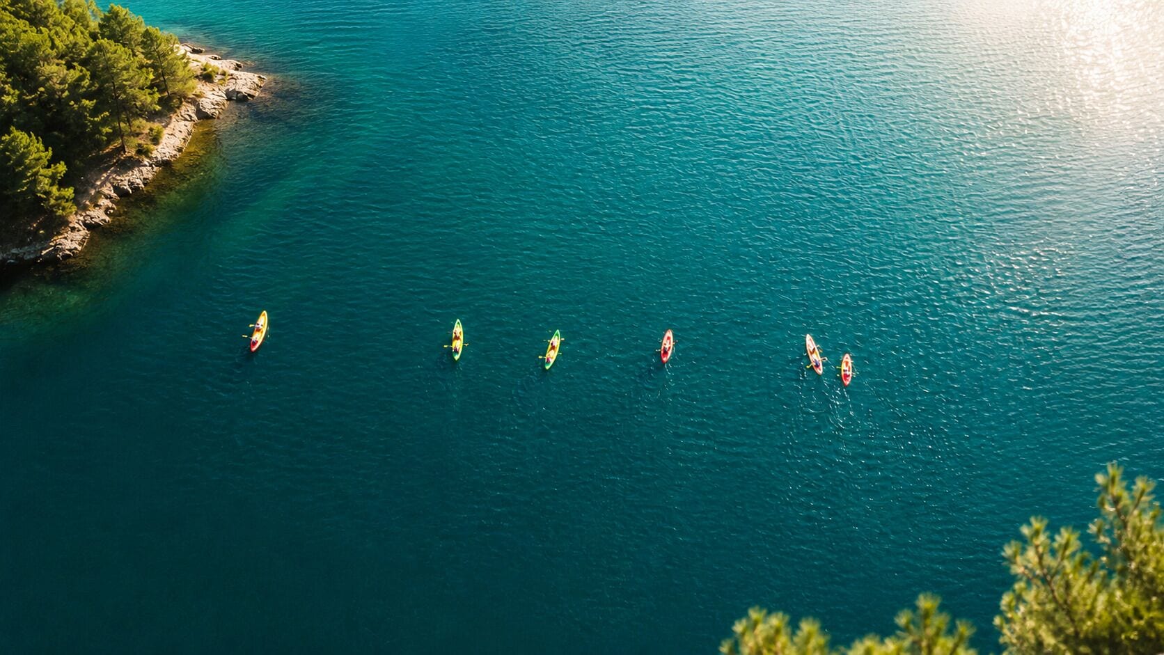 Vista despejada de una zona costera con una hilera de kayaks en el agua.