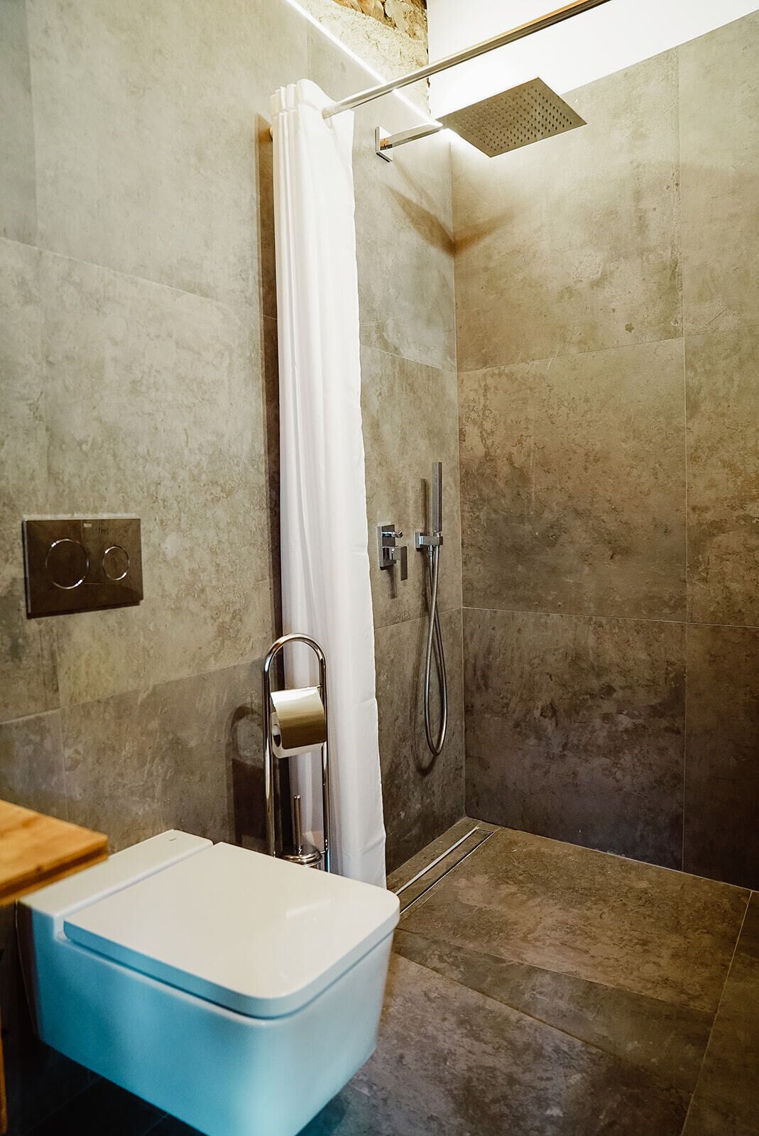 A modern bathroom with a shower, a toilet, and a towel rack.