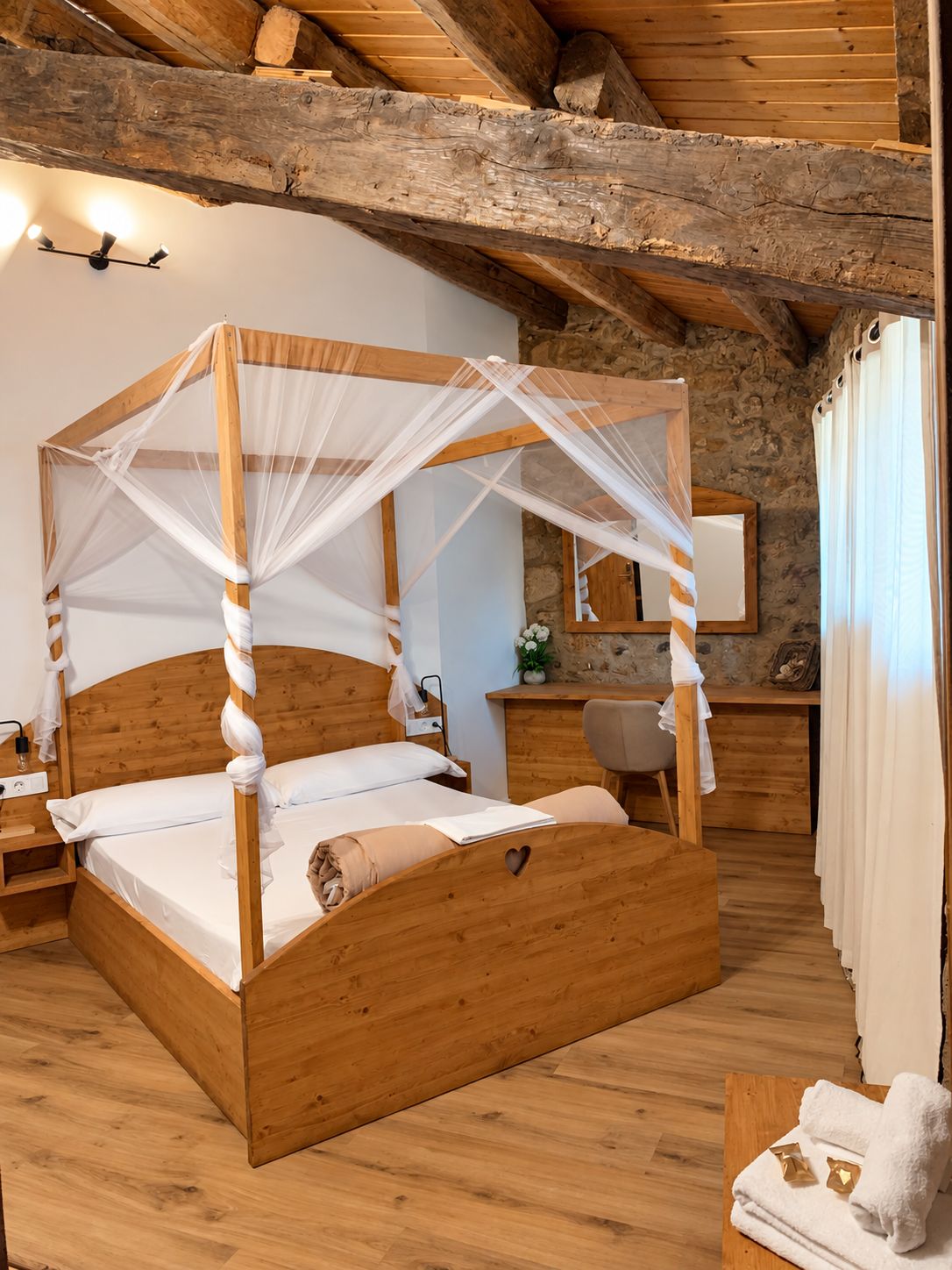 A wooden four-poster bed with a canopy, a bedside table, a mirror, and a small desk with a chair.