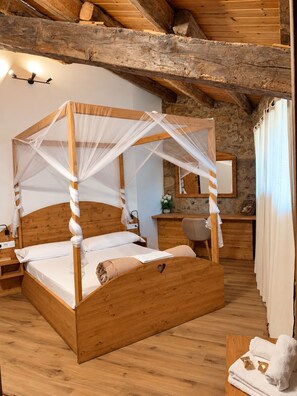 A wooden four-poster bed with a canopy, a bedside table, a mirror, and a small desk with a chair. - Cases Altes de Posada (Navès)