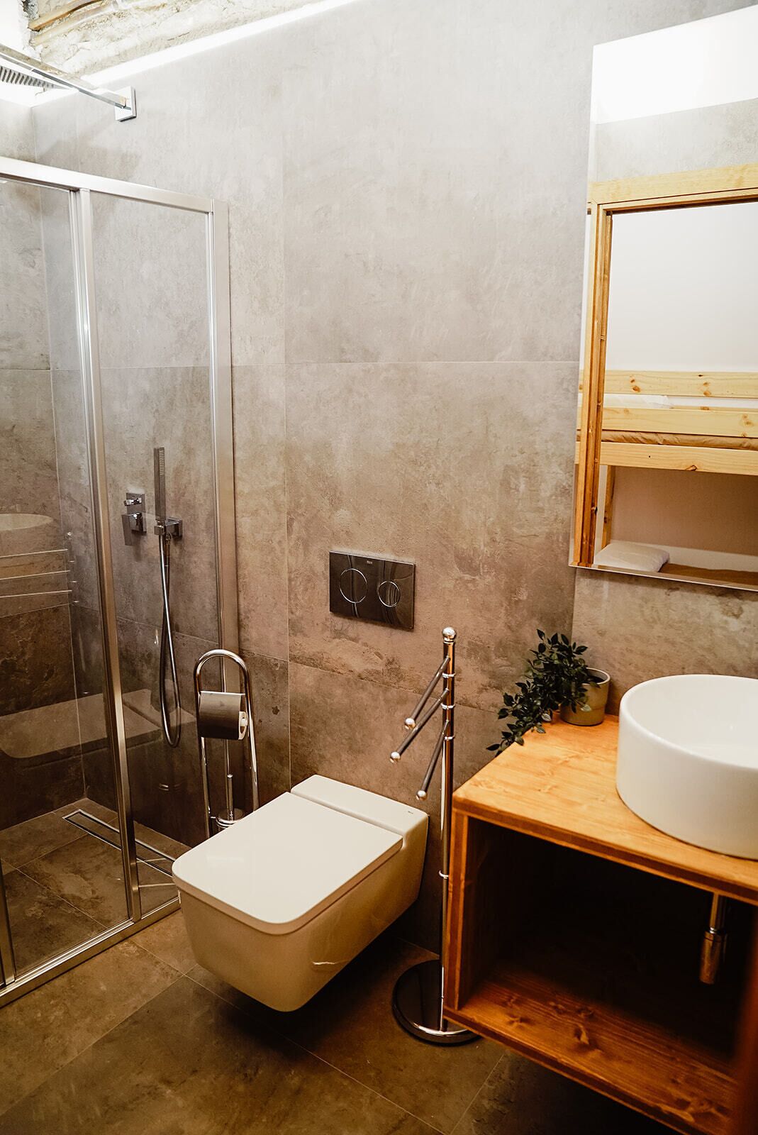 Ein Badezimmer mit Duschkabine aus Glas, Toilette, Waschbecken mit Holzschrank und Spiegel über dem Waschbecken.