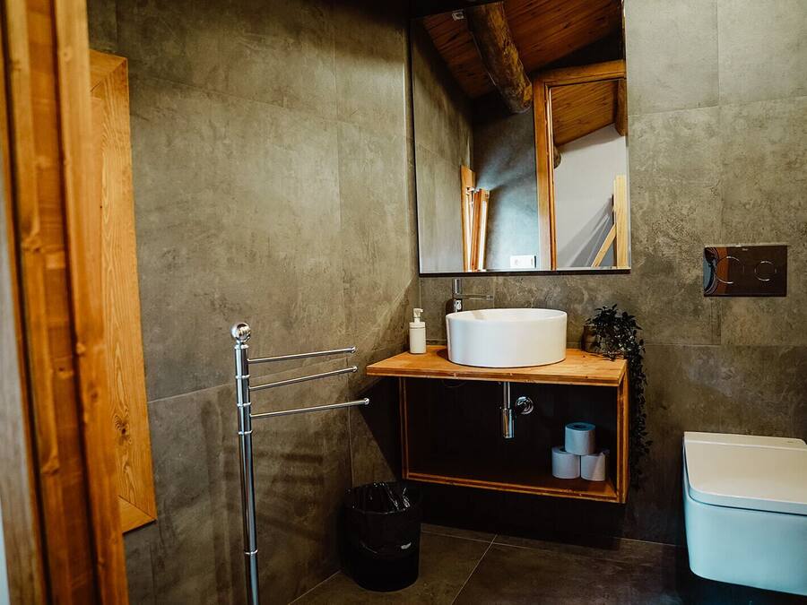 Un baño con tocador de madera, un lavabo blanco, un espejo y un inodoro.