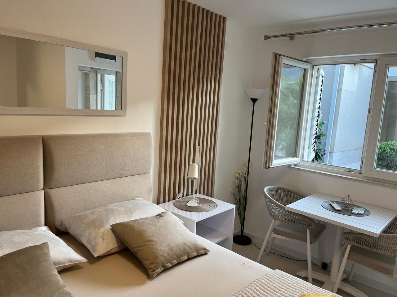 A modern bedroom with a large bed, bedside tables, a desk, and a chair.