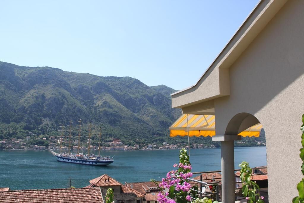 Ein Balkon mit Blick auf einen See, ein Segelschiff und Berge im Hintergrund.
