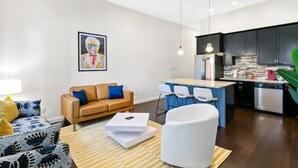 Un salon moderne comprenant un canapé, une table basse et un coin repas avec des chaises.