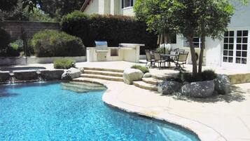 Een buitenzwembad, een zwembad met een waterval