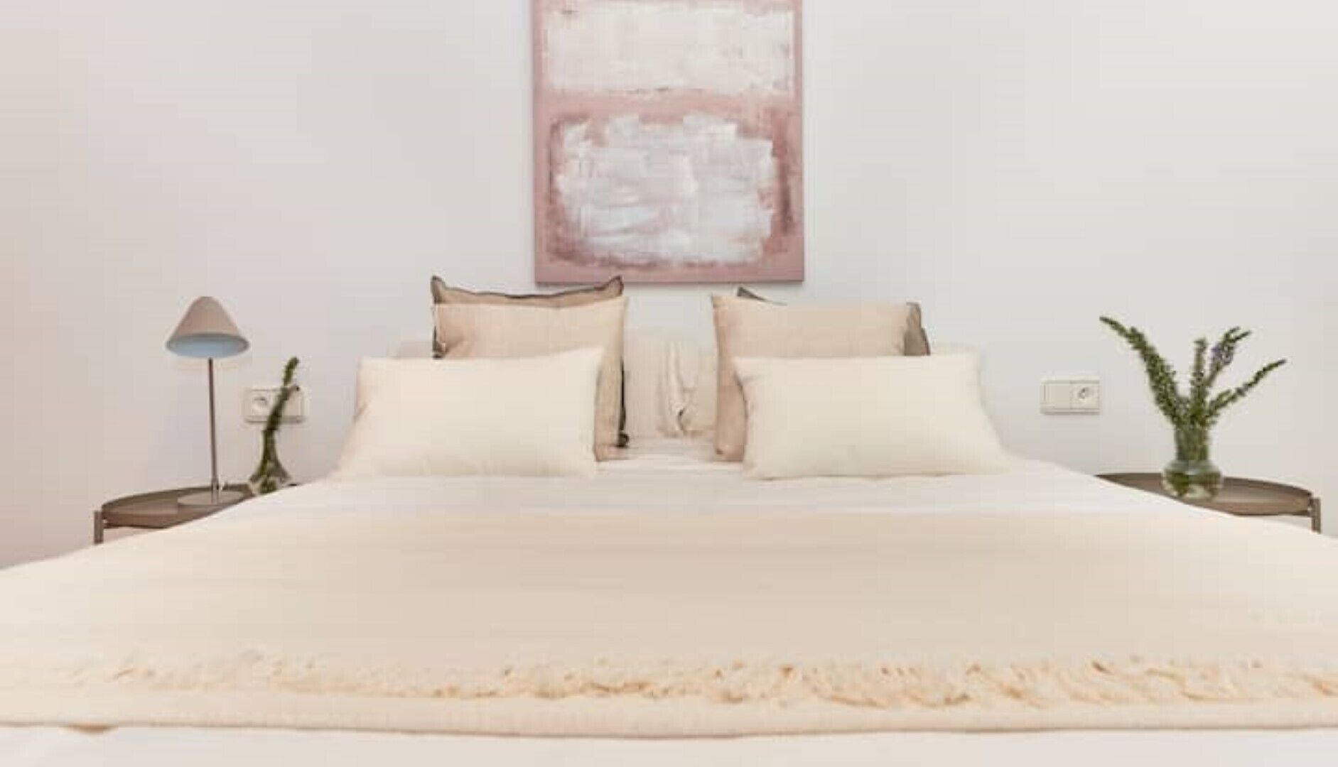 Ein Schlafzimmer mit einem großen Bett, zwei Nachttischen, einer Lampe und einem Wandbild.