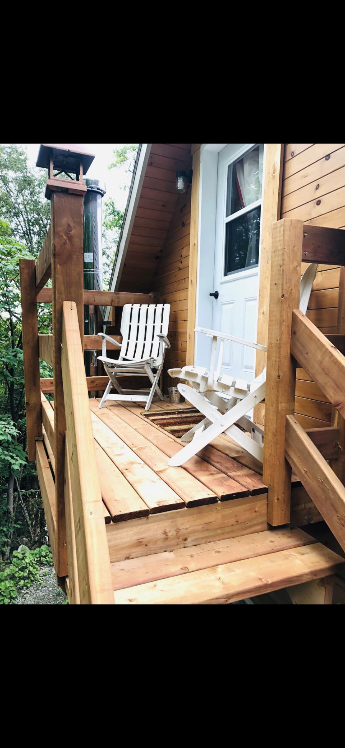A wooden deck with a white Adirondack chair and a wooden bench.