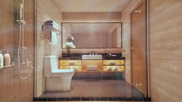 A modern bathroom with a glass partition, a toilet, a sink, and a shower area.