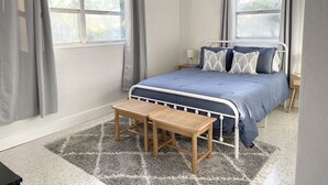 A bedroom with a bed, a nightstand, a desk, and a ceiling fan. - Bohemian Bungalow on Byron Road (Fort Myers)