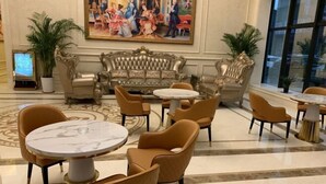 Eine Lobby mit einem klassischen Sofa, runden Tischen und bequemen Sesseln.