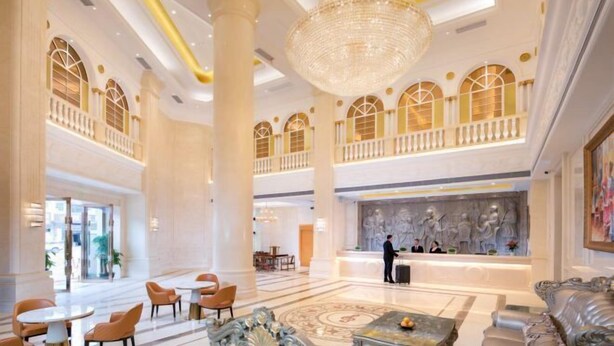 Eine geräumige Lobby mit hohen Decken, Kronleuchtern und klassischen Säulen.