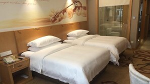 Ein Hotelzimmer mit zwei Betten, einem hölzernen Kopfteil, einem Nachttisch mit Telefon und einem floralen Teppich.