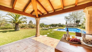Eine Terrasse im Freien mit Pool, Palmen und Tisch, gedeckt mit Speisen und Getränken.