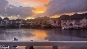 A waterfront property with multiple buildings, a dock, and a calm body of water reflecting the sunset.