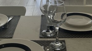 A dining area with a view of a marina, a white table set with plates and glasses, and a wicker chair.