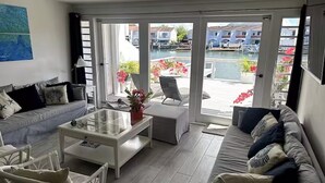 A modern living room with a glass door leading to a balcony overlooking a marina.