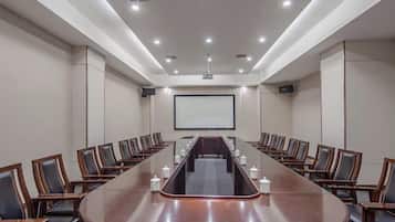 A conference room with a long table, chairs, a projector screen, and a whiteboard.