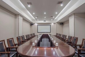 A conference room with a long table, chairs, a projector screen, and a whiteboard. - Xiangxiang Hotel (Xiangxiang)