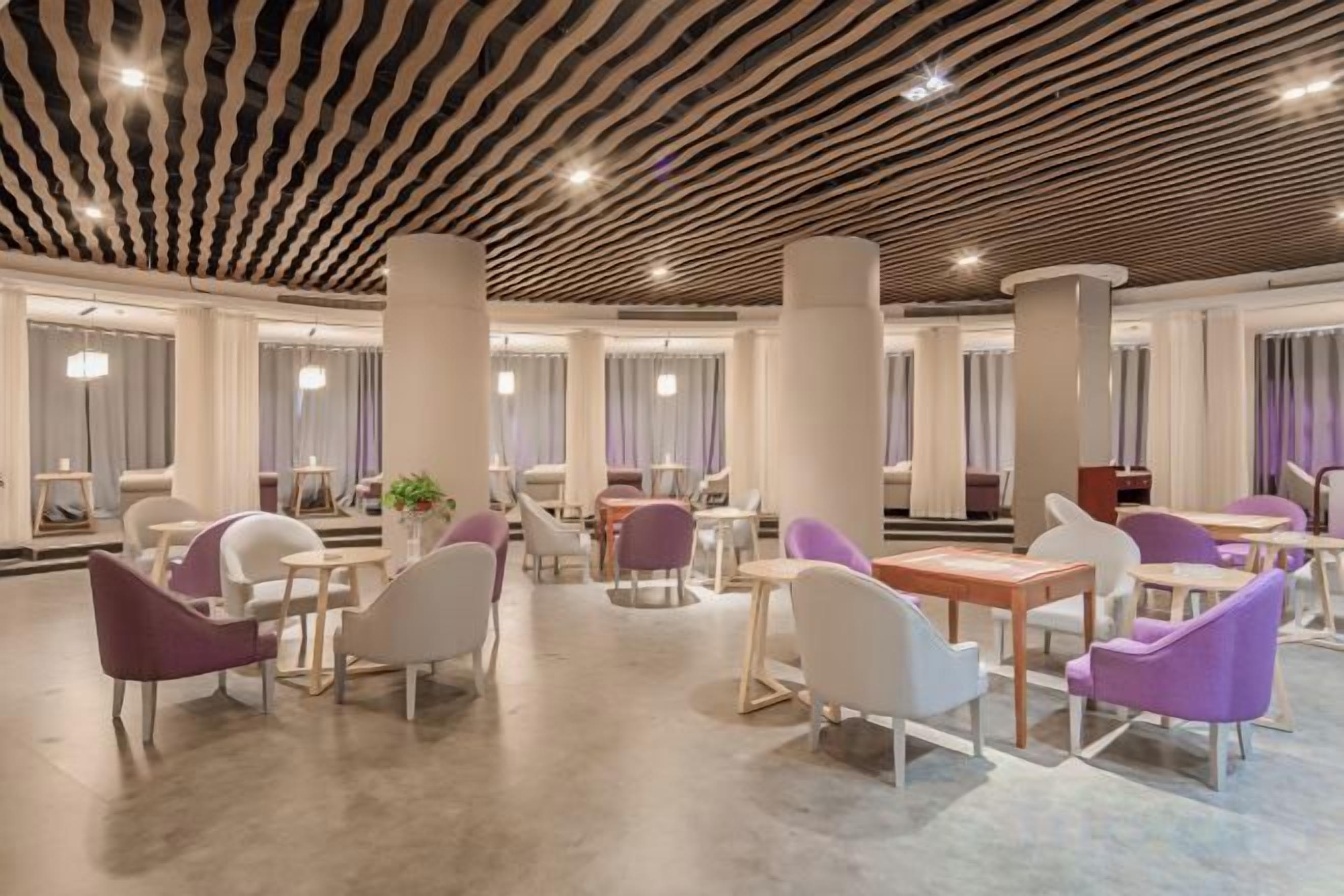 A spacious lobby with modern furniture, large columns, and a patterned ceiling.