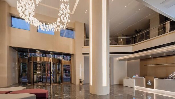 A spacious lobby with a revolving door, a reception desk, and a high ceiling with a modern light fixture. - Xiangxiang Hotel (Xiangxiang)