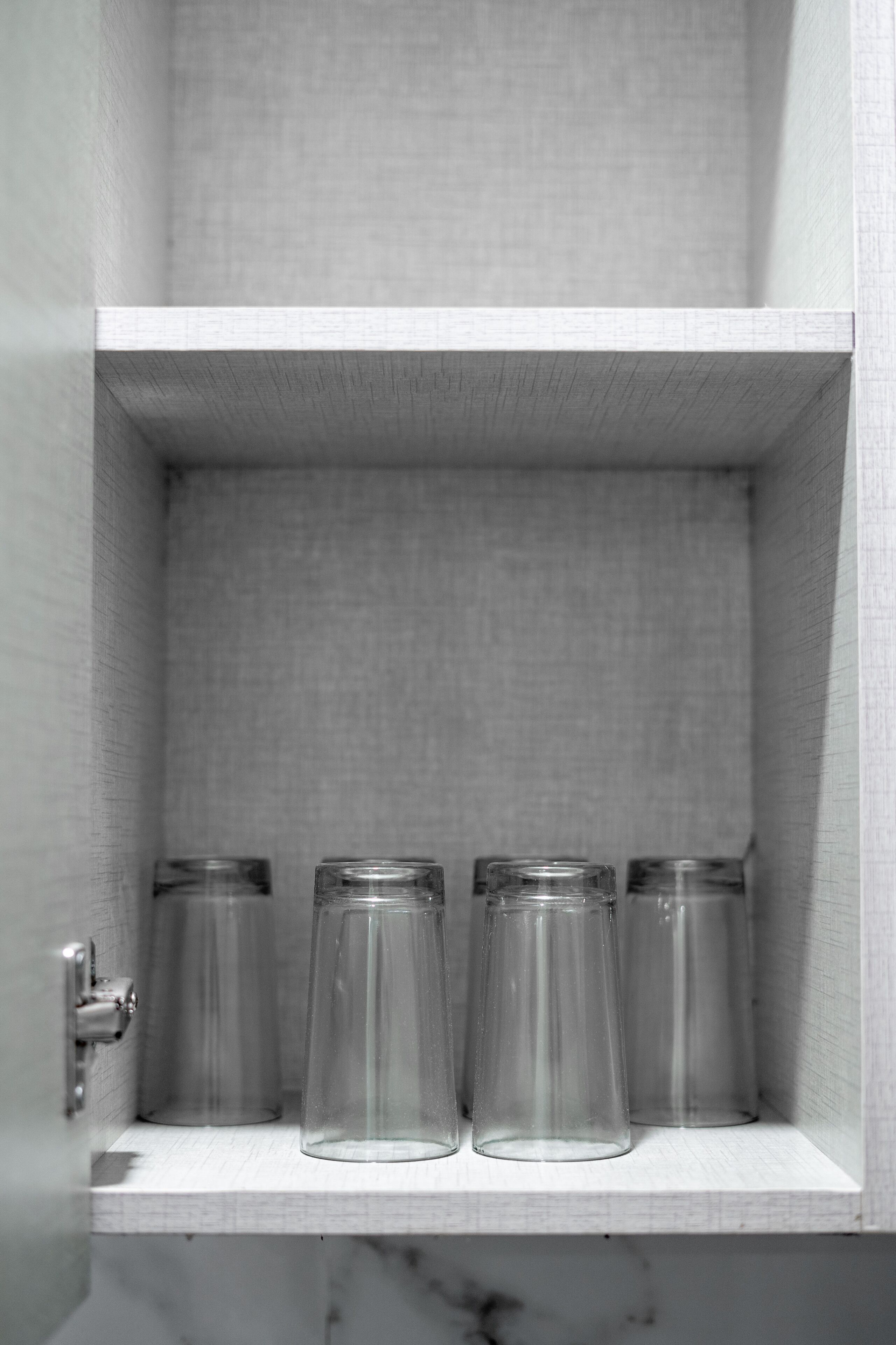 Une étagère blanche avec quatre bocaux en verre transparent.