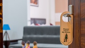 Une porte en bois avec une pancarte indiquant : « Veuillez faire le ménage dans ma chambre. »