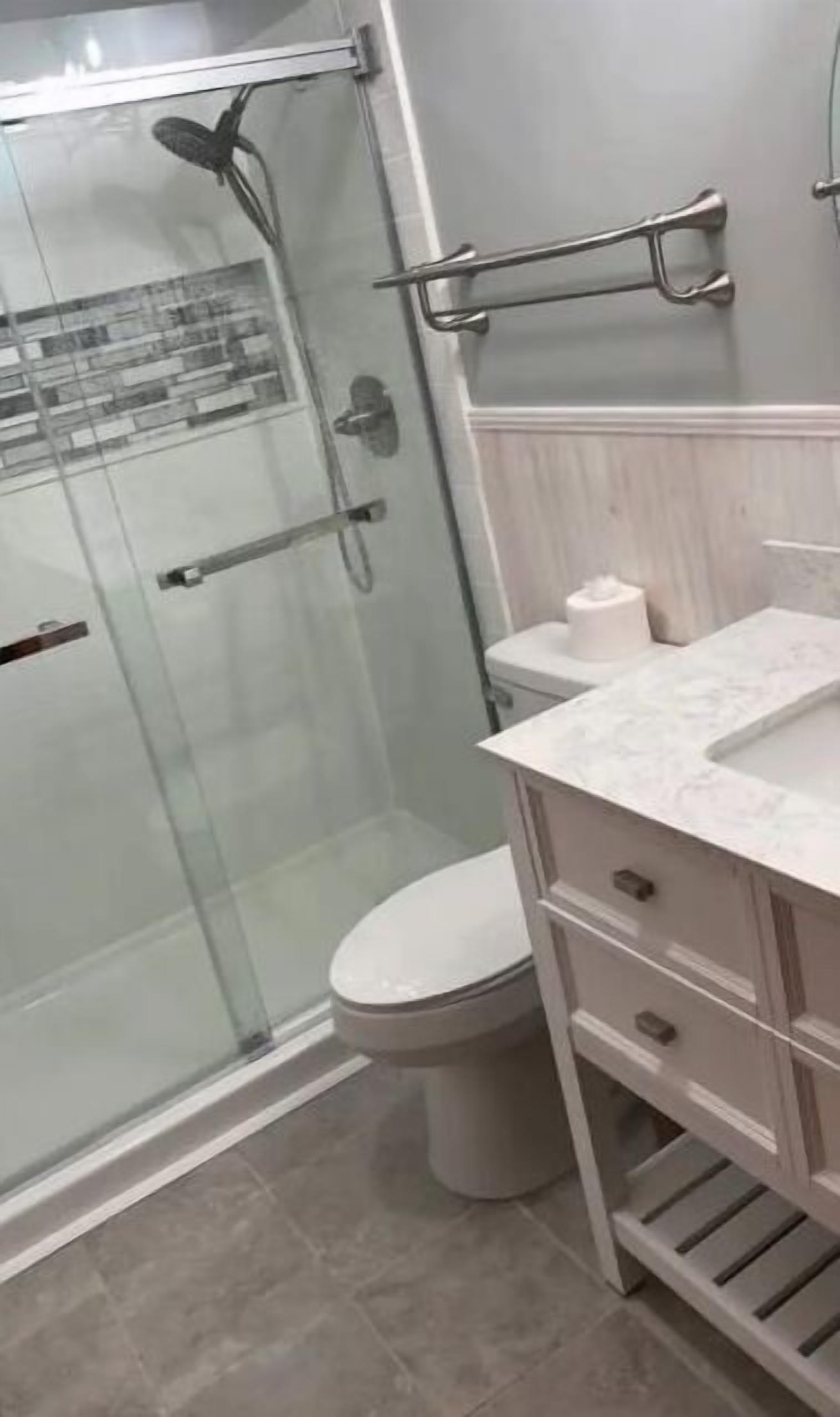 A modern bathroom with a glass shower enclosure, a toilet, and a vanity with a sink.