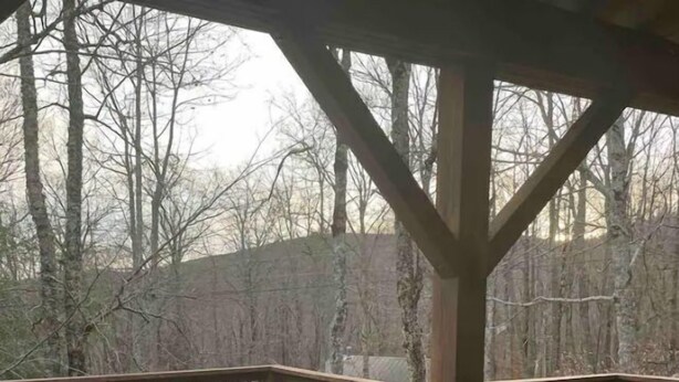 Un jacuzzi en una terraza de madera con vista a árboles sin hojas.