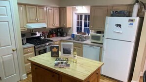 Una cocina con armarios de madera, estufa, microondas y refrigerador.