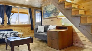 A cozy cabin interior with a wooden staircase, a sofa, a small table, and a cabinet. - Misty View (Rumney)