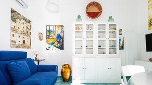 Ein Zimmer mit einem blauen Sofa, weißen Schränken und einer großen Vase.