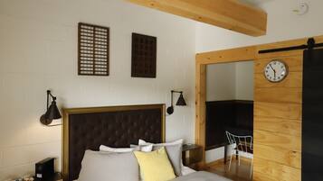 A bedroom with a bed, bedside tables, a clock, and a chair.