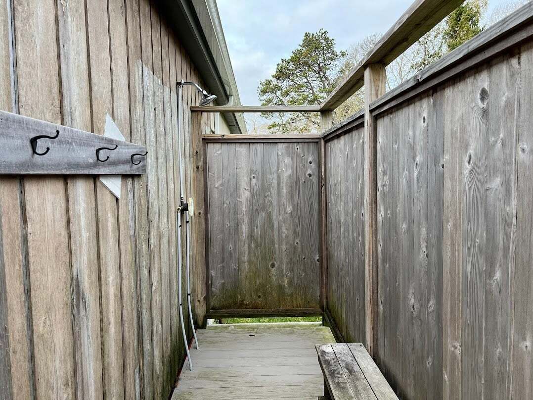 A narrow wooden corridor with a bench and a door at the end.