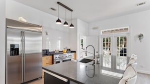 Una cocina moderna con electrodomésticos de acero inoxidable, una isla central con pileta y luminarias colgantes.
